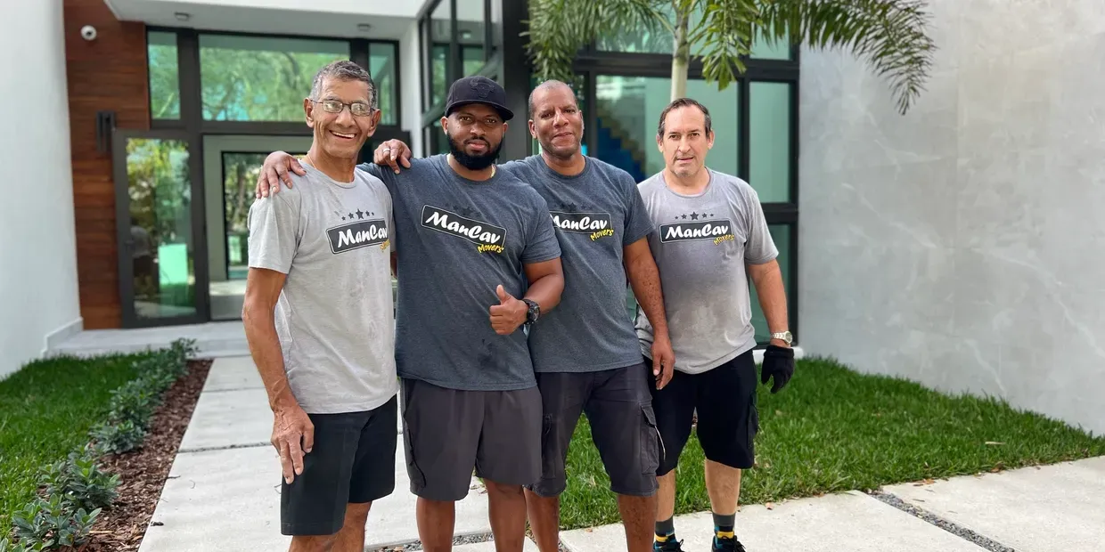 Four ManCav Movers crew members in company t-shirts outside a Miami home