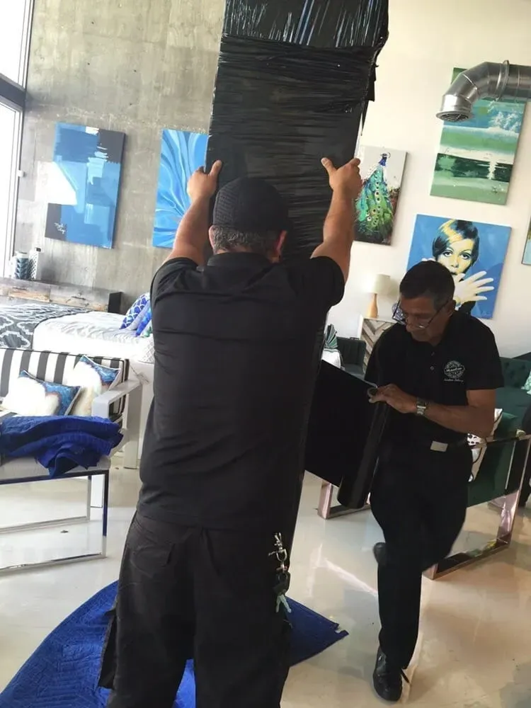 Movers carrying wrapped furniture in a modern apartment