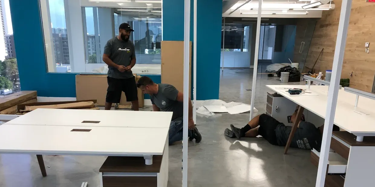 Movers assembling office furniture in a commercial space