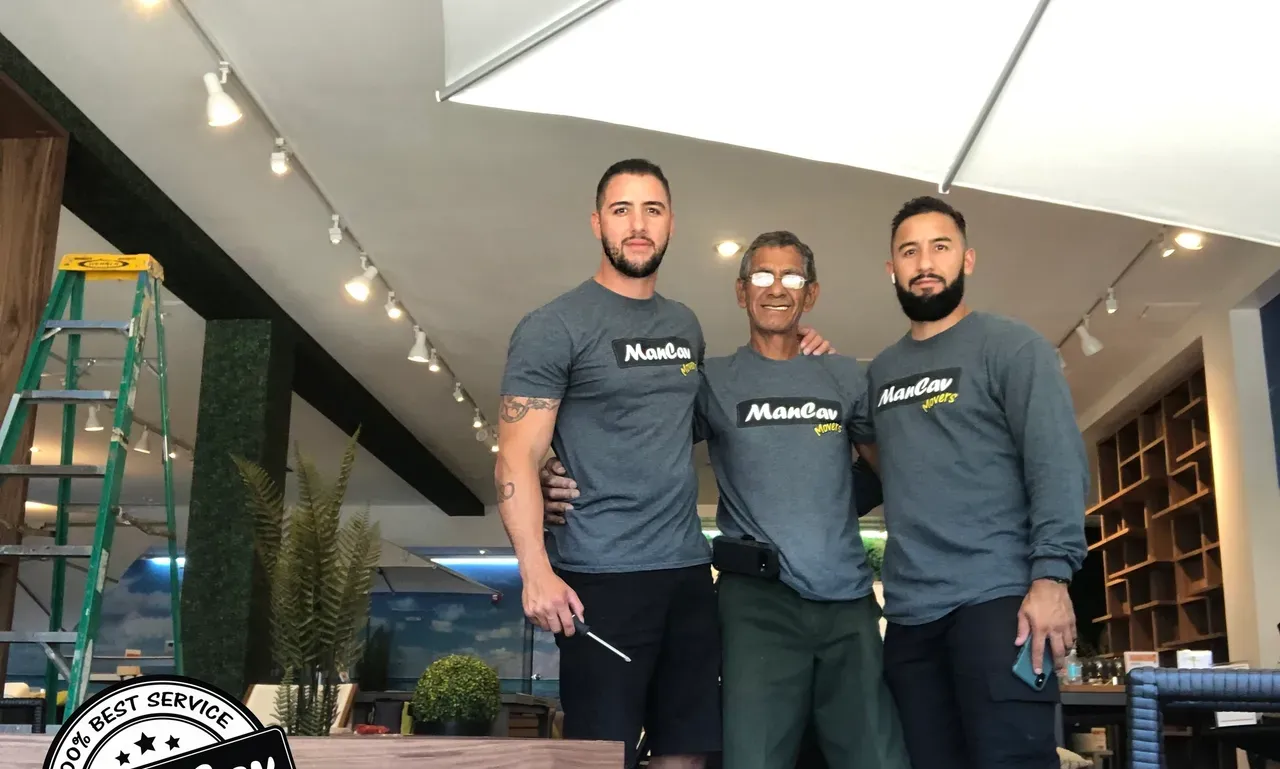Three ManCav Movers crew members in company t-shirts inside a home