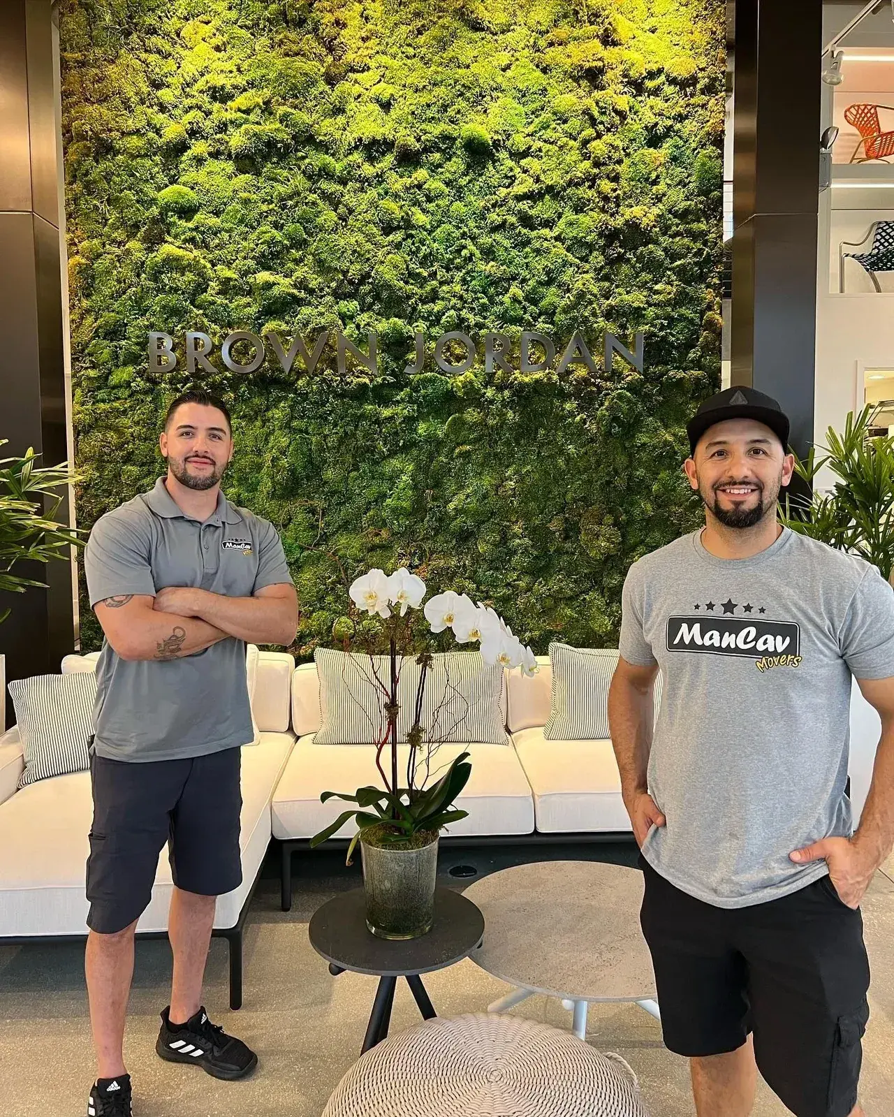 Two ManCav Movers crew members in company t-shirts in a building lobby