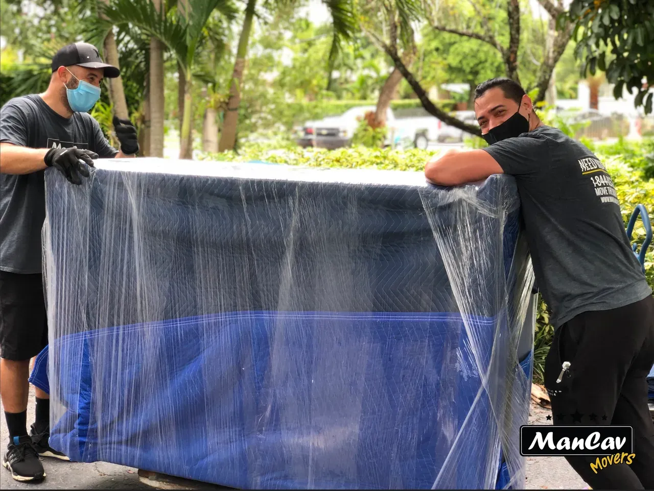 ManCav Movers crew wrapping furniture in moving blankets and plastic