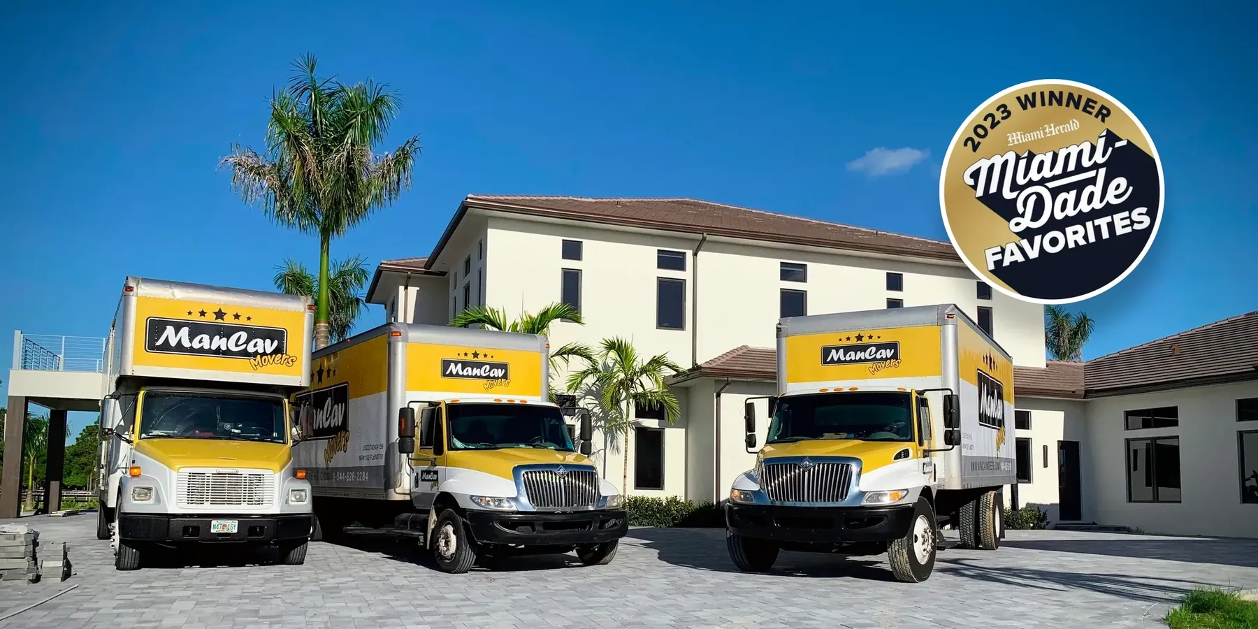 Three ManCav Movers trucks parked in front of a Miami home