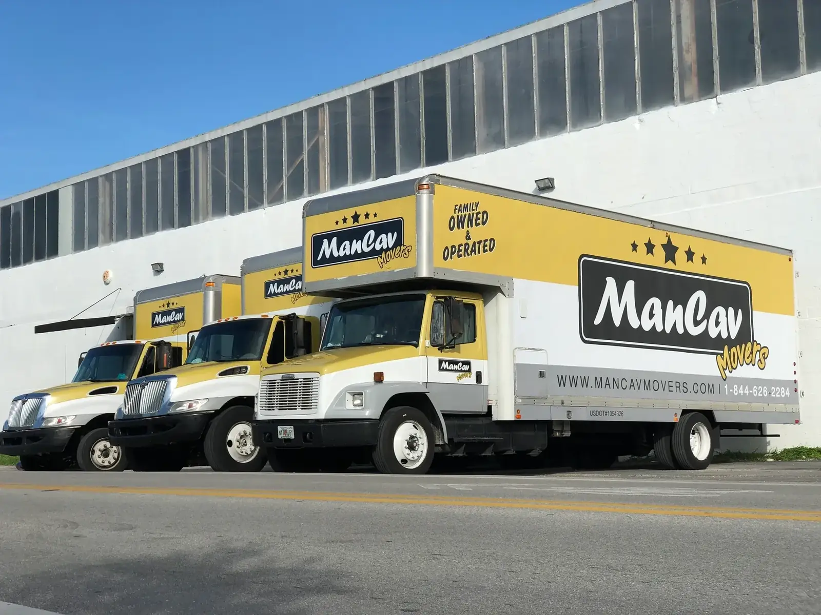 ManCav Movers trucks lined up outside a warehouse building
